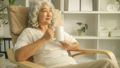 older woman sitting alone at home with coffee reflecting on loss of community and social disconnection