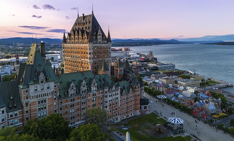 Aerial view of Fairmont Le Château Frontenac overlooking the St. Lawrence River and Old Québec City at sunset.