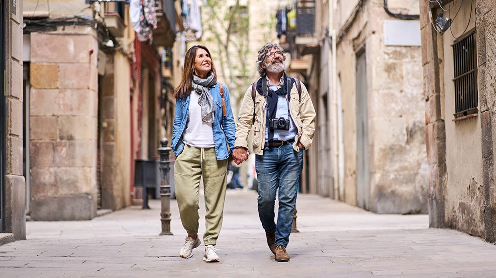 Thinking About Retiring Overseas? Read This First. 3 Retired couple holding hands exploring narrow European street during expat retirement