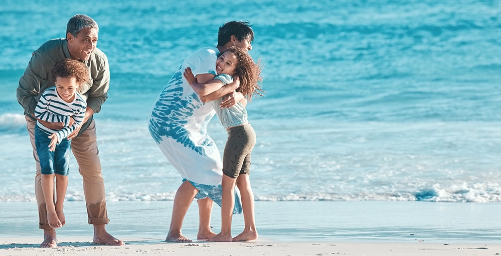 Thinking About Retiring Overseas? Read This First. 2 Grandparents enjoying active beach time with grandchildren, showing the family moments retirees may miss when living abroad