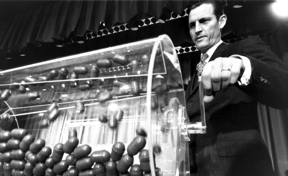 Draft lottery official drawing numbered capsules from rotating drum during Vietnam War selective service lottery 1970