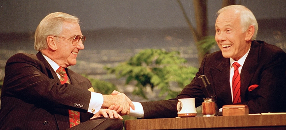 Johnny Carson and Ed McMahon laughing together on The Tonight Show set