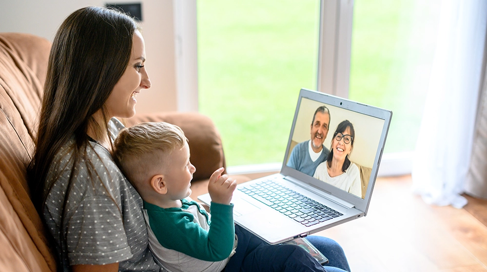 Young mother and toddler video calling grandparents on a laptop — long-distance grandparenting still supports brain health