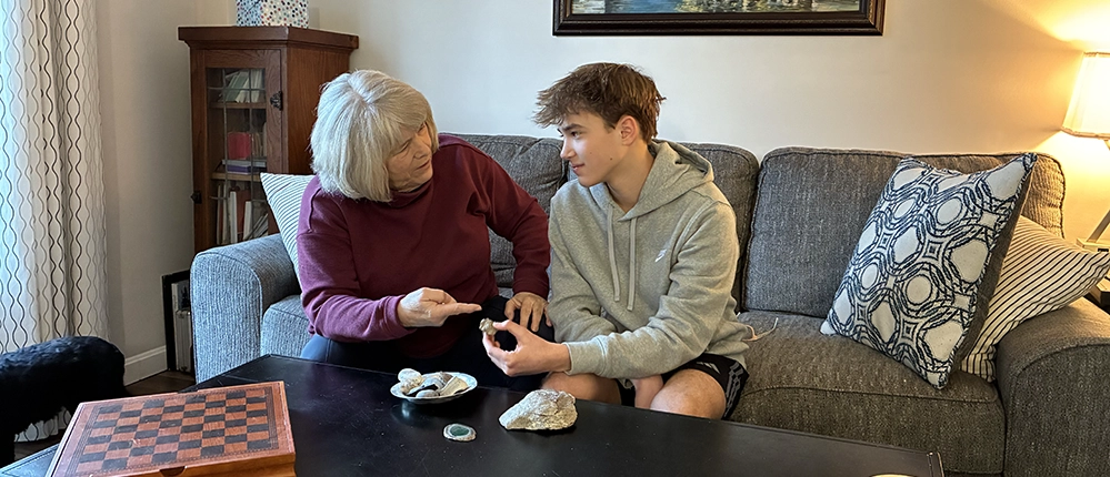 Grandmother and teenage grandson sitting on a couch, sharing rocks collected from trips around the world