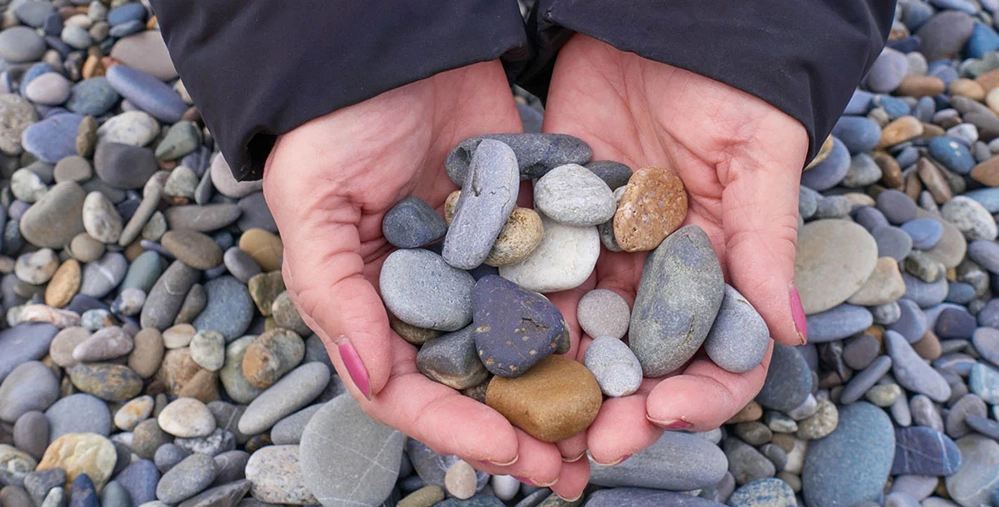 Hands cupping colorful smooth rocks collected from travels around the world