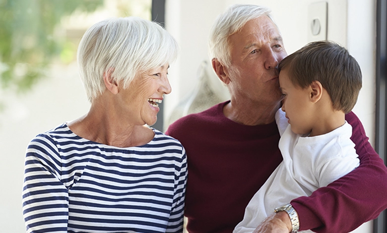 Grandparents smiling with young grandson — babysitting your grandkids is linked to better brain health