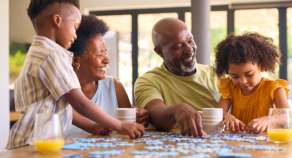 Grandparents and grandchildren working on a jigsaw puzzle together — the kind of mentally stimulating activity linked to better cognitive health