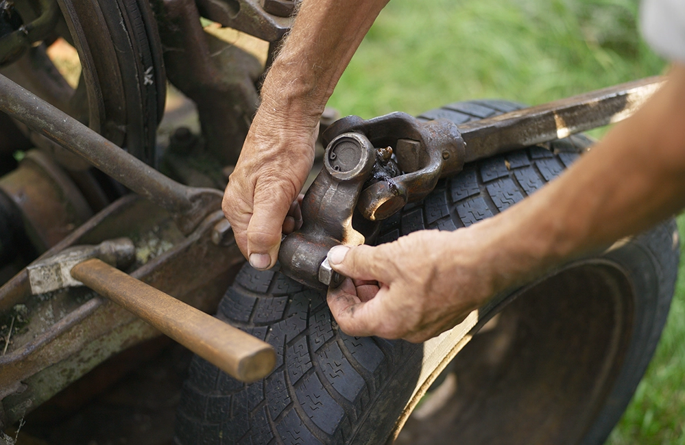 Weathered hands repairing farm equipment outdoors
