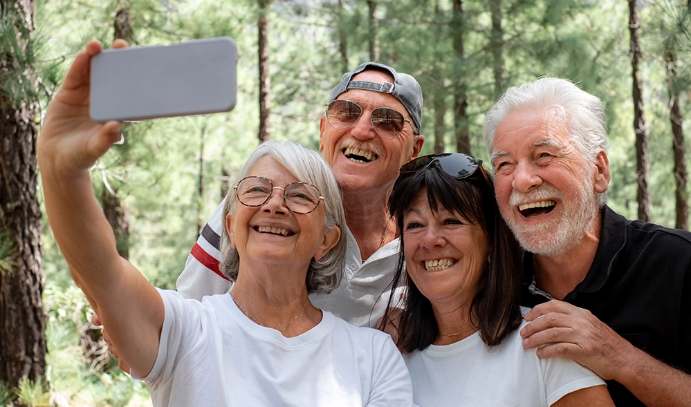 Group of older friends laughing together taking a selfie outdoors — social engagement in retirement 