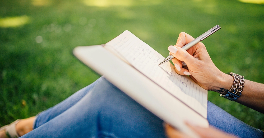 Woman writing in a journal outdoors, planning a second career after retirement