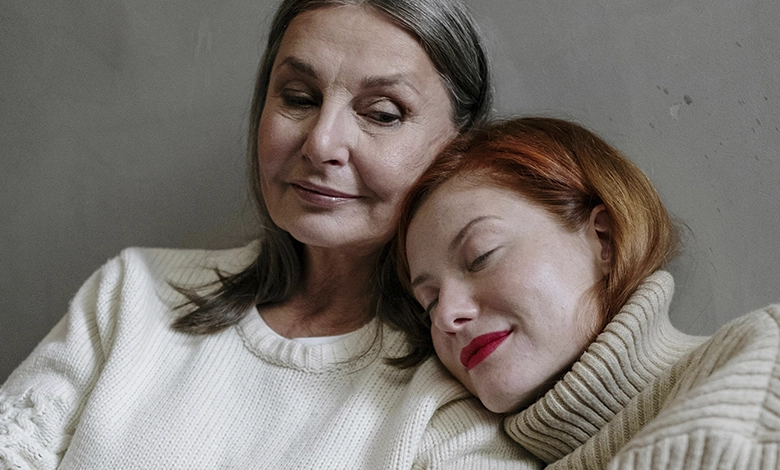 Adult daughter resting on mother's shoulder, sharing a quiet moment of connection at home