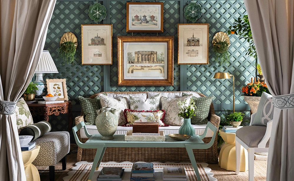 Elegant designer room vignette by Ashleigh Graber Design at The STUDIO Dallas featuring a teal lattice wall, framed architectural prints, and a rattan sofa with layered pillows