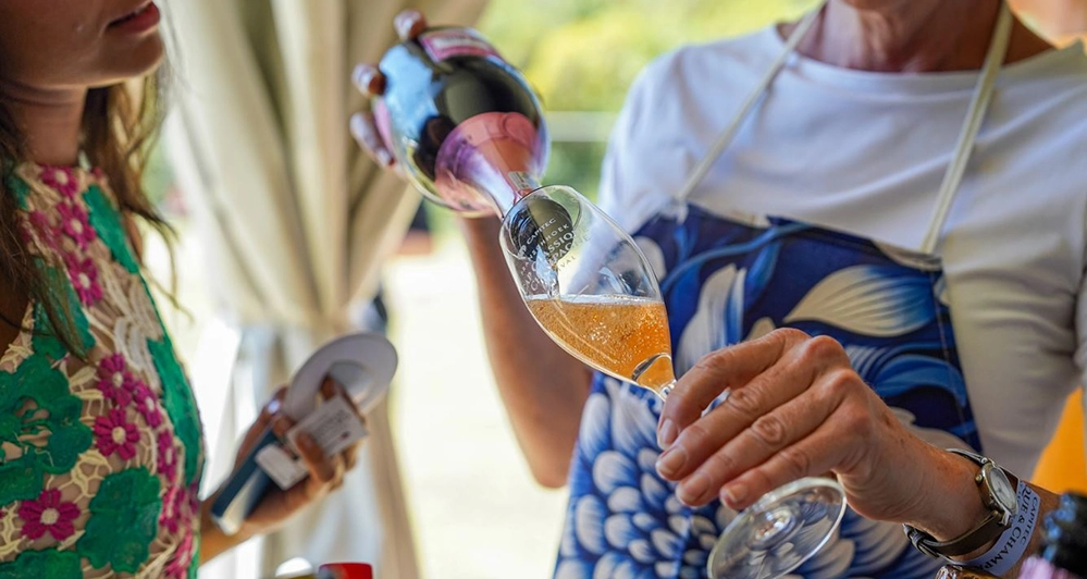 Woman pouring sparkling wine into a glass at Cap Classique Festival 