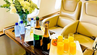 Champagne bottles, mimosas, and white roses on a table inside a Cirrus Aviation private jet cabin.