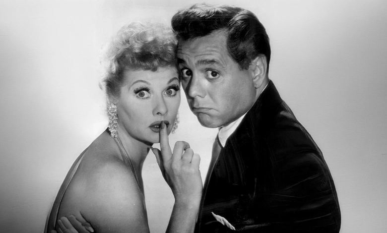 Lucille Ball with finger to her lips and Desi Arnaz looking exasperated in a playful 1957 I Love Lucy promotional portrait