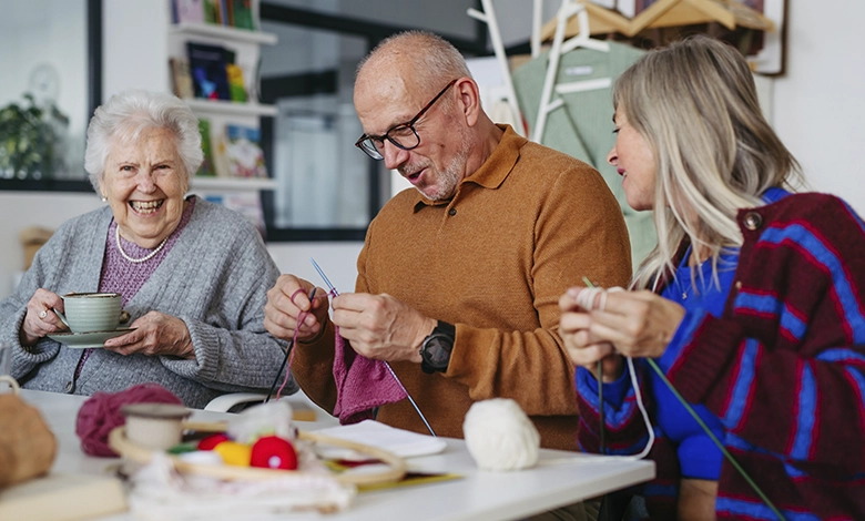 Older adults in a knitting class, one man focused on his stitches — staying curious is the secret to happiness after 50