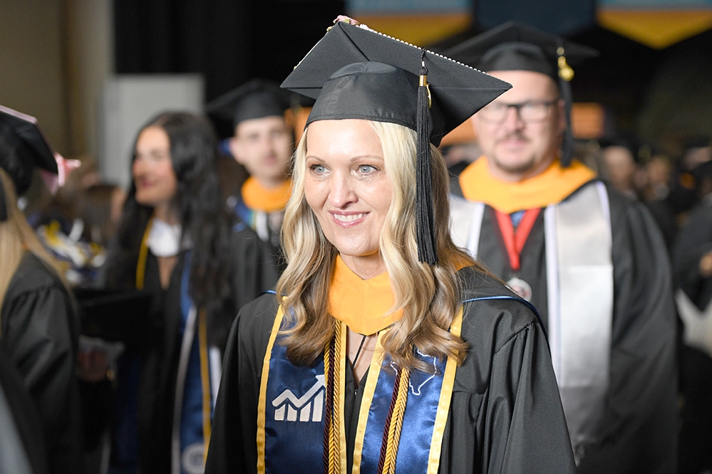 Tammy France smiling in cap and gown during graduation procession at SNHU commencement