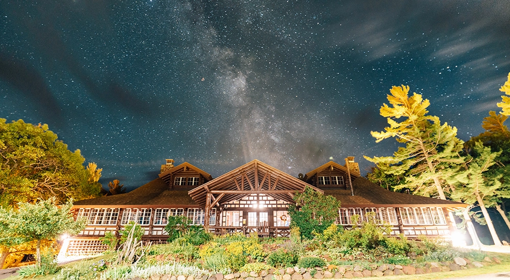 Keweenaw Mountain Lodge lit up at night beneath the Milky Way — the heart of Michigan’s dark sky destination