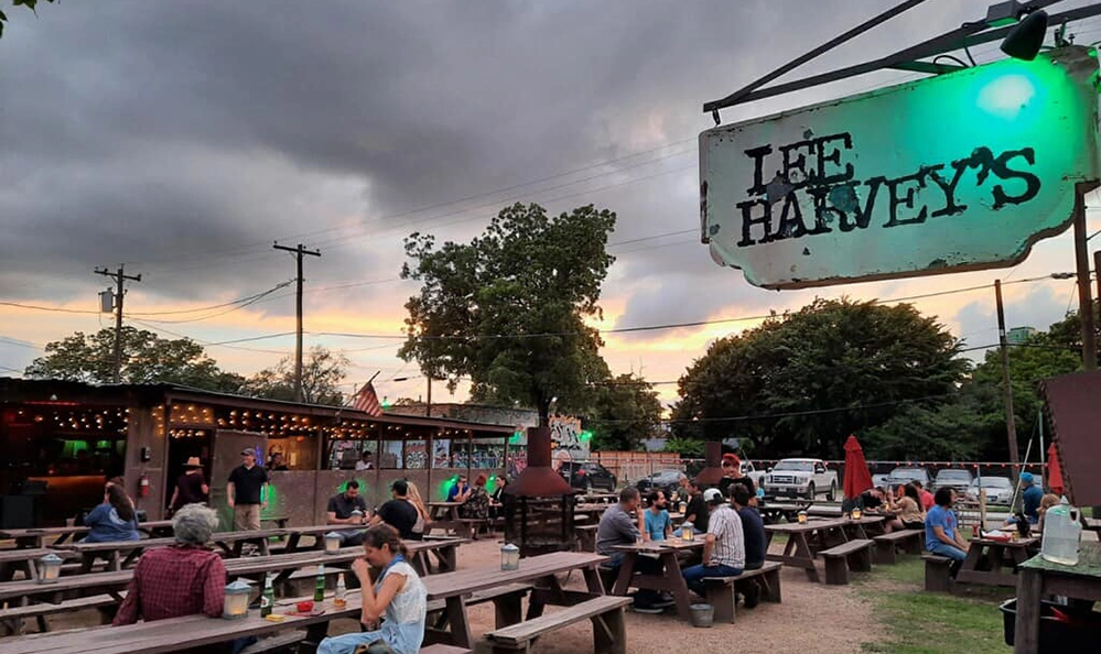 DARTable Sips: The Best Bars and Rooftops You Can Reach on DART This Summer 3 Crowded outdoor patio with picnic tables and string lights at Lee Harvey's dive bar in the Cedars neighborhood of Dallas
