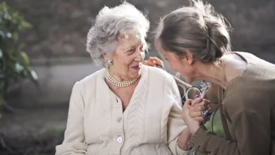 An older woman and her adult daughter hold hands and talk warmly outdoors, a picture of the connection at the heart of caring for aging parents.