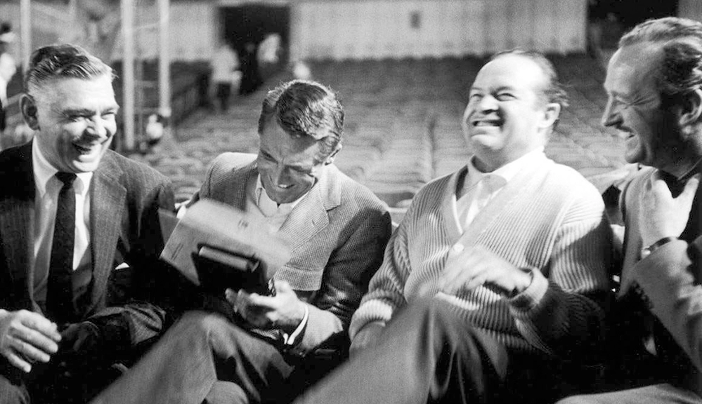 Cary Grant laughing alongside Clark Gable, Bob Hope, and David Niven in the 1950s.