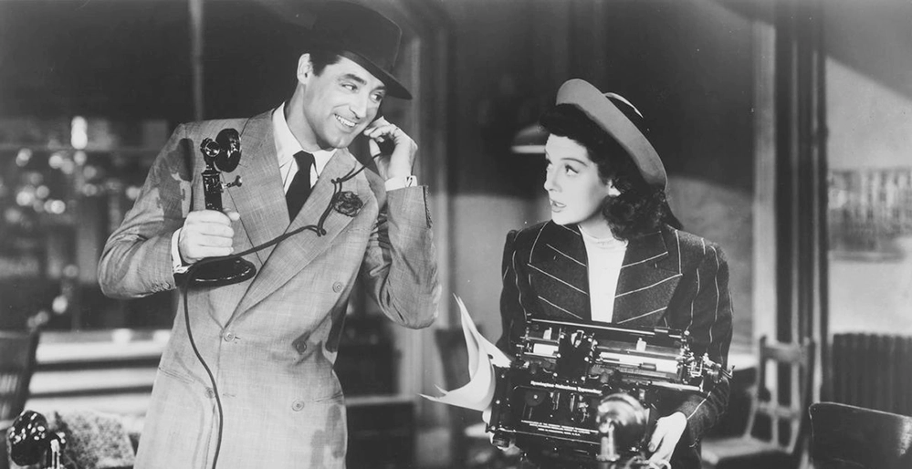 Cary Grant on a candlestick phone beside Rosalind Russell holding a typewriter in His Girl Friday, 1940.