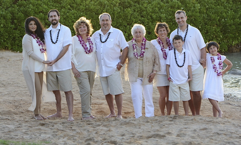 A multigenerational family posing on the beach at sunset in Hawaii