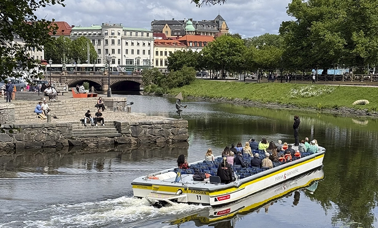Paddan sightseeing boat cruising a Gothenburg canal past historic waterfront buildings on a summer day