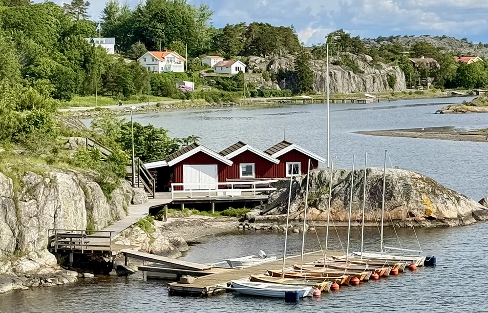 Red boathouses and moored sailboats beside the bridge connecting Styrsö and Donsö in Gothenburg’s archipelago