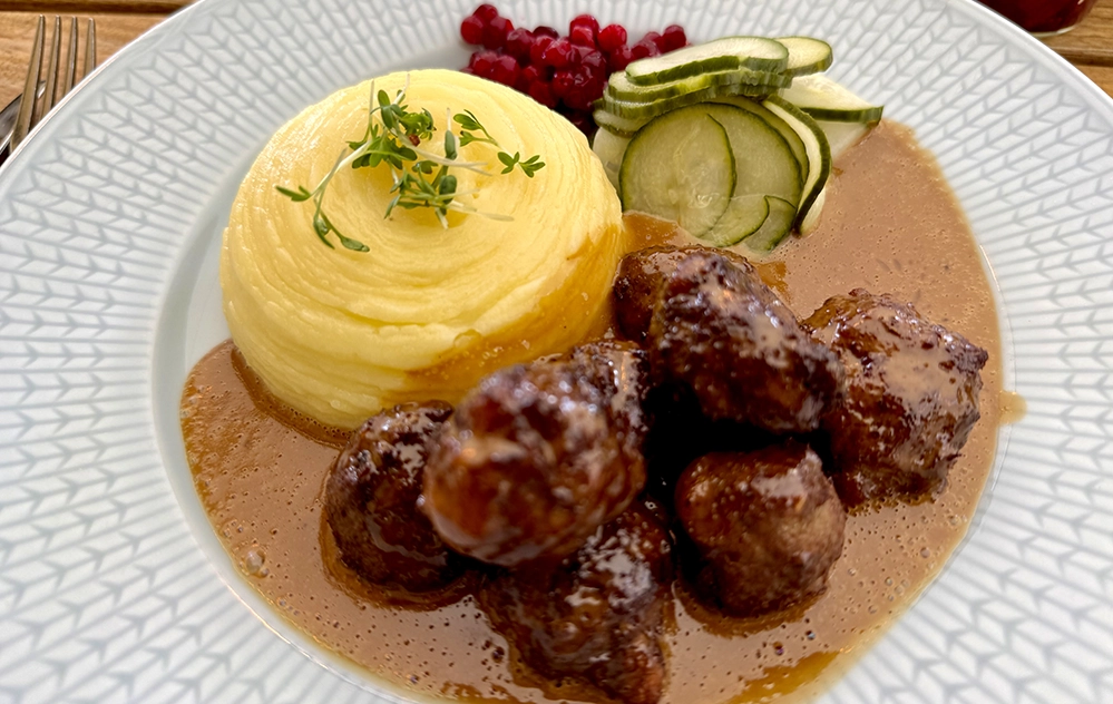 A plate of traditional Swedish meatballs with lingonberries, cream sauce and cucumber at Långa Raden in Stockholm