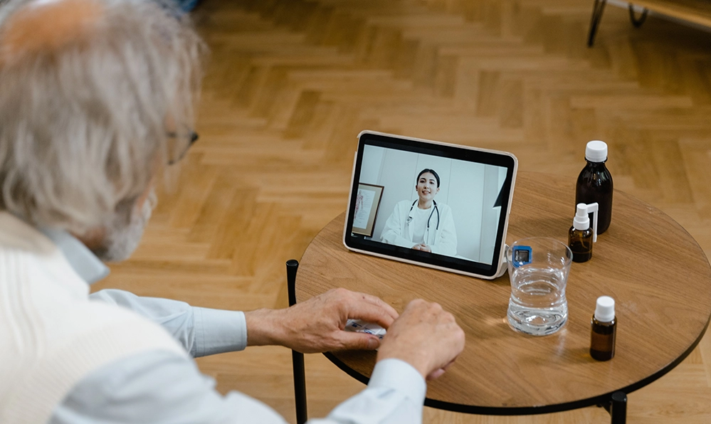 Caring for Aging Parents at Home: A Practical Guide for Adult Children 2 An older gentleman during a telehealth video call with a doctor at home, one way technology eases caring for aging parents.