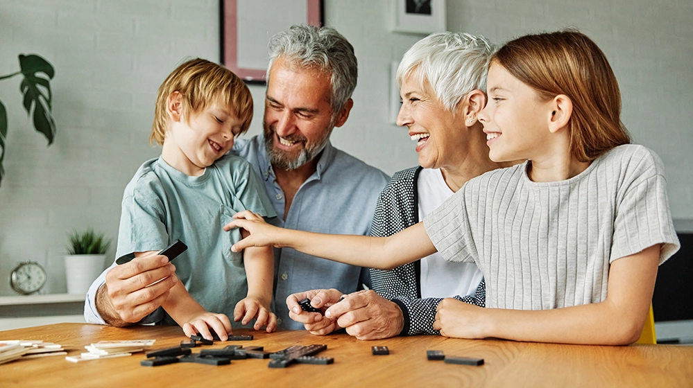 Grandparents and two grandchildren playing a game together at a table at home