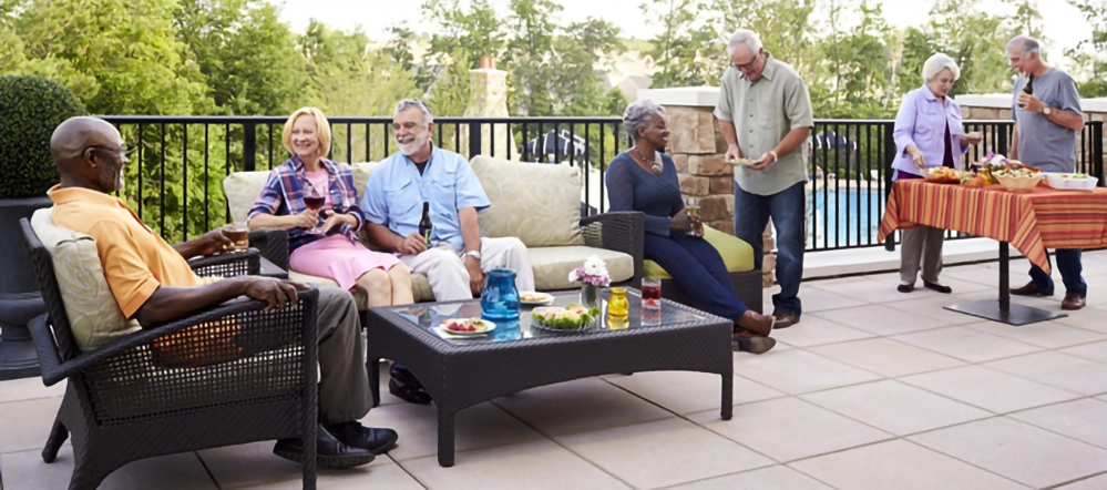 Neighbors gathered on an outdoor patio with food and drinks at a Del Webb community