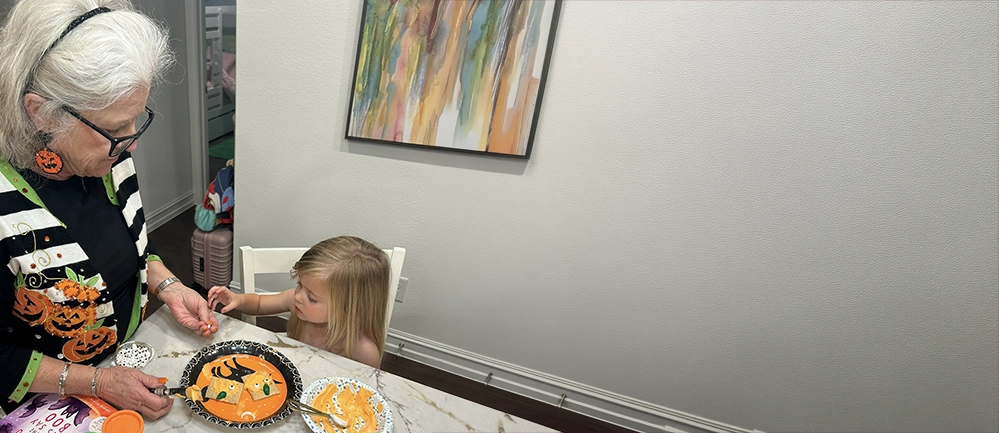Grandmother and her granddaughter decorating treats together at the kitchen counter