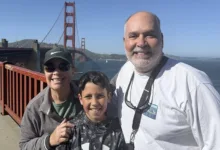Grandmother, grandson and grandfather smiling on the Golden Gate Bridge walkway with the bridge and bay behind them