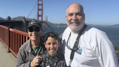 Grandmother, grandson and grandfather smiling on the Golden Gate Bridge walkway with the bridge and bay behind them