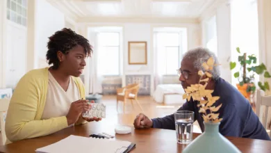 Caregiver and older man reviewing his medications together at a dining table