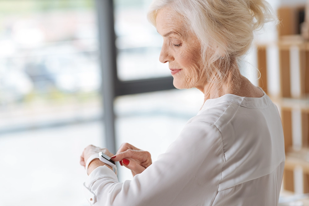 Managing Chronic Conditions After 65: Systems That Hold 4 Older woman checking her smartwatch