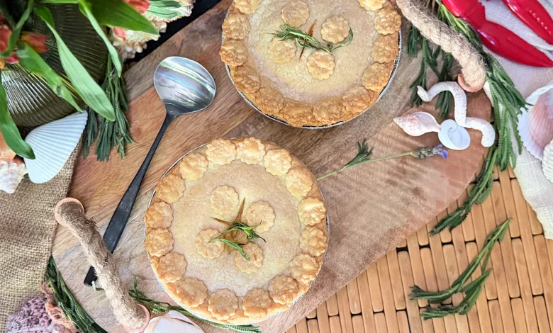 Two crab and corn pot pies with scalloped pastry edges and fresh tarragon on a wooden board