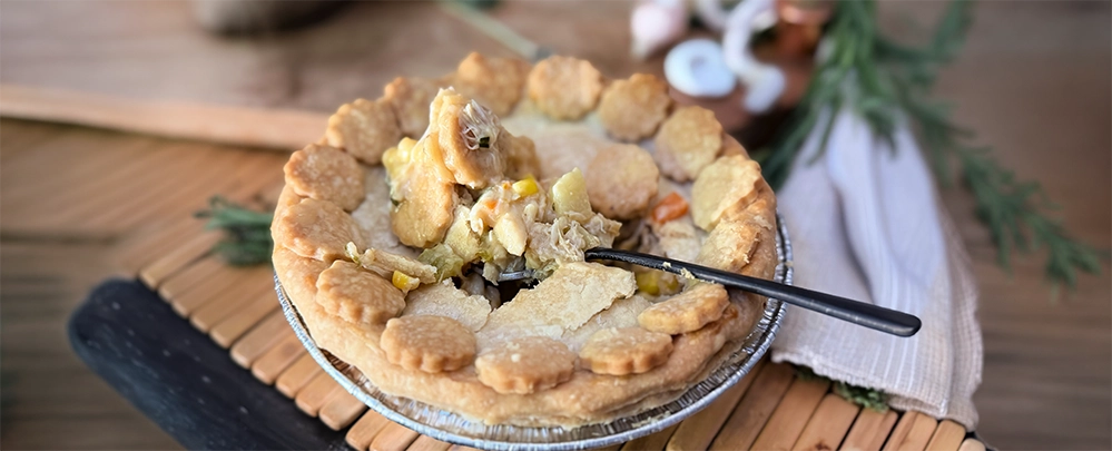 A crab and corn pot pie opened with a fork, showing crab, corn, and potato in cream sauce